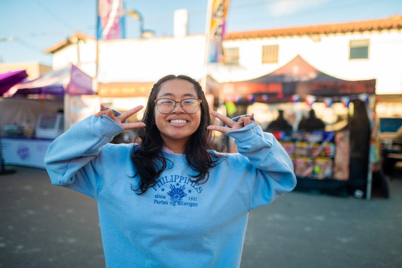 Picture of Sarah, Kilig Ko founder, at an event, doing peace sign and wearing the Philippine Perlas ng Silangan Light blue sweater