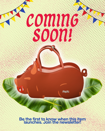 A promotional graphic with a brown pig-shaped handbag centered over green banana leaves. The image includes the text 'coming soon!' at the top and 'Be the first to know when this item launches.