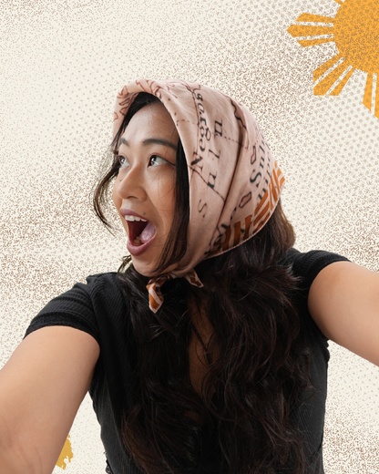 Woman wearing mapa scarf as headscarf with a textured beige background.